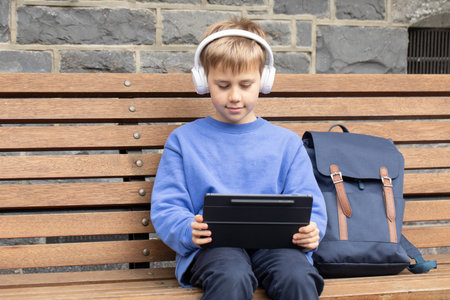 Focused boy student with headphones watches video lesson