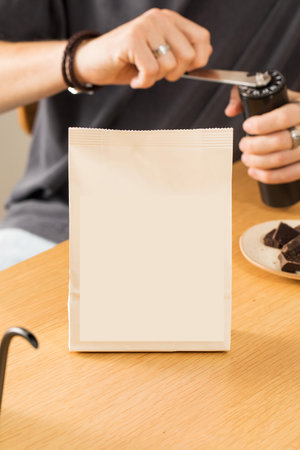 Blank paper bag near man barista grinding coffee beansの写真素材