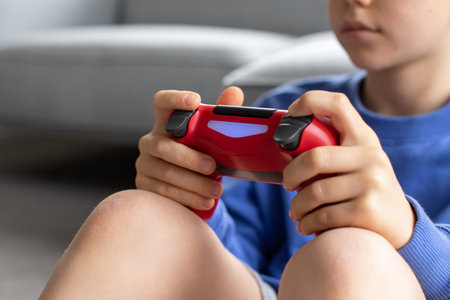 The boy holds a joystick in his hand and is intently playing a video game. Video games.