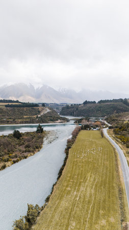 River mouth surrounded by fields located in valley among mountainsの写真素材