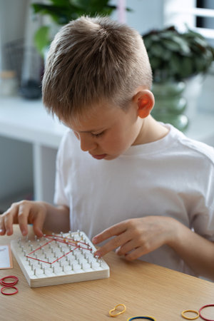 A Child Actively Engaged in a Fun Creative Rubber Band Art Activity Within His Home Environmentの写真素材