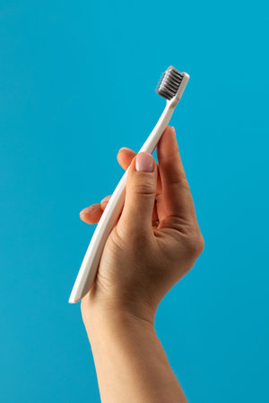 Woman holds vibrant toothbrush firmly on blue backgroundの写真素材