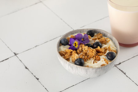 A healthy nutritious breakfast of natural Greek yoghurts, granola and fresh berries on tile...