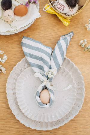 Easter egg wrapped in linen napkin in the shape of bunny with ears. Happy Easter