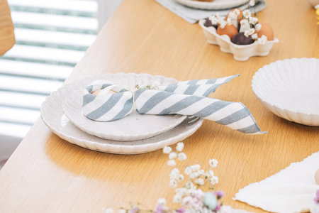 Easter egg wrapped in linen napkin in the shape of bunny with ears. Happy Easter