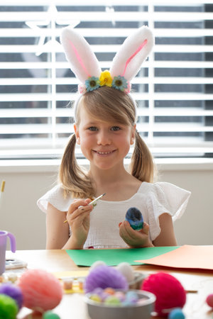 Happy little girl coloring easter egg wearing bunny ears headband. Happy Easter
