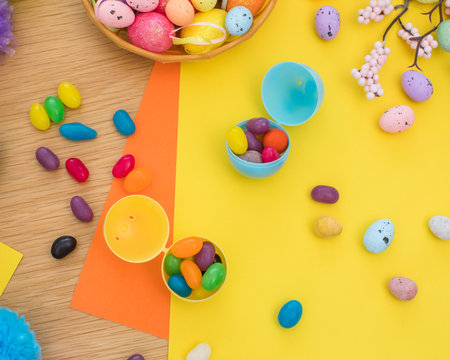 Bright background with candies in the form of Easter eggs in plastic eggs. Egg hunt concept. Happy Easter. Top view.の写真素材