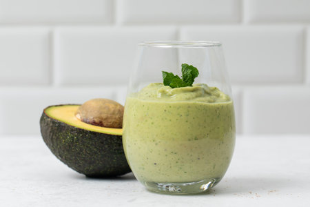 Refreshing avocado smoothie with mint and half avocado on white backgroundの写真素材