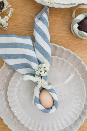 Easter egg wrapped in linen napkin in the shape of bunny with ears. Happy Easterの写真素材