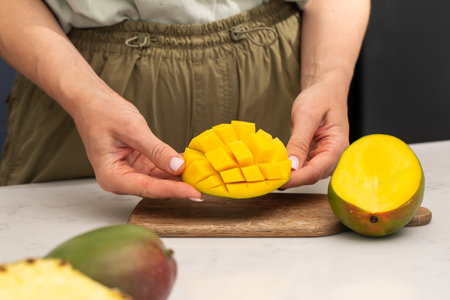 Woman holding ripe and juicy cut mango in her hands. Tropical fruitsの写真素材