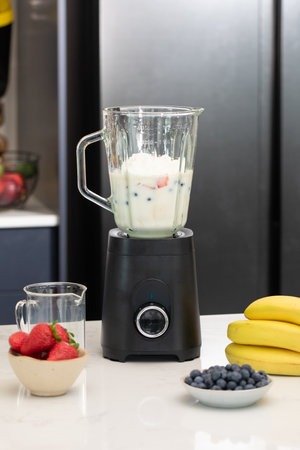 Making a fresh berry smoothie in modern kitchen setting for healthy lifestyle inspirationの写真素材