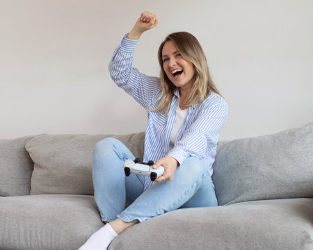 Excited young woman plays videogame in living roomの写真素材