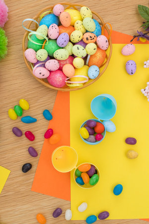 Bright background with candies in the form of Easter eggs in plastic eggs. Egg hunt concept. Happy Easter. Top view.の写真素材