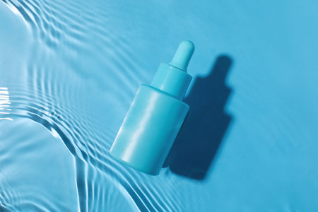 Blue serum bottle on water surface. Face serum mockup. Beauty concept.の写真素材