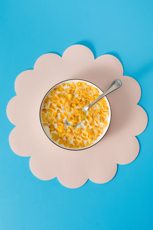 Cornflakes with milk in a bowl on a blue background. Breakfast cereal