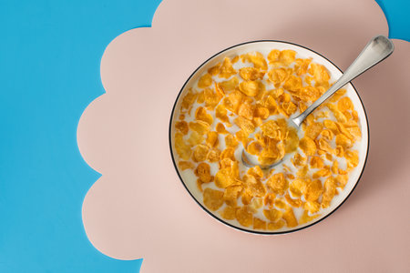Cornflakes with milk in a bowl on a blue background. Breakfast cereal