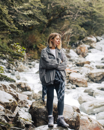 Stylish young woman in outdoor clothing standing on rocks. Concept of active lifestyle.の写真素材