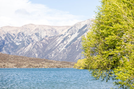 Serene mountain lake with lush foliage and majestic peaks