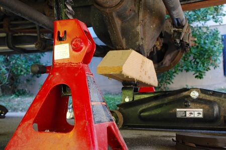 A red automotive jack stand is bracing a vehicle for mechanical workの写真素材