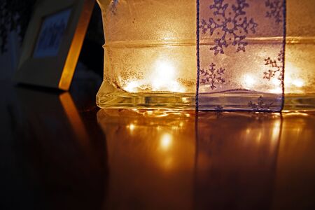 Glass box lit up with reflection glowing on wood table surfaceの写真素材