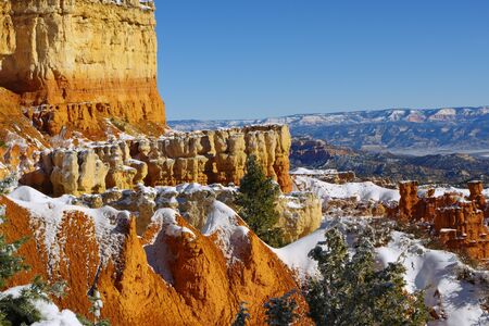 Bryce Canyon Hoodoos displaying their beauty of reds and yellows while surrounded by greens, blues and whiteの写真素材