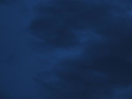 Cloudy nighttime sky in shades of midnight blue to royal blueの写真素材