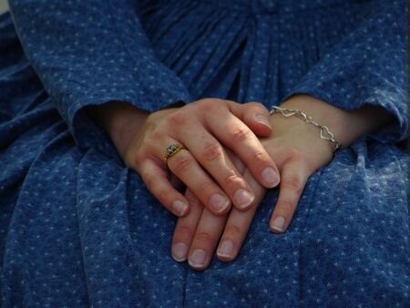 The hands of a seated young woman wearing a blue print dressの写真素材