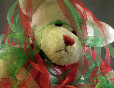 teddy bear covered in green and red ribbons overwhelmed with wrapping giftsの写真素材
