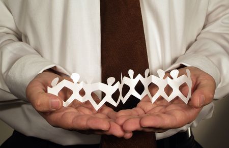 Business man holding cut out paper people 