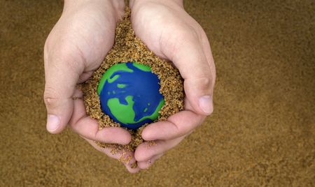 hands holding sand with small green and blue earth の写真素材