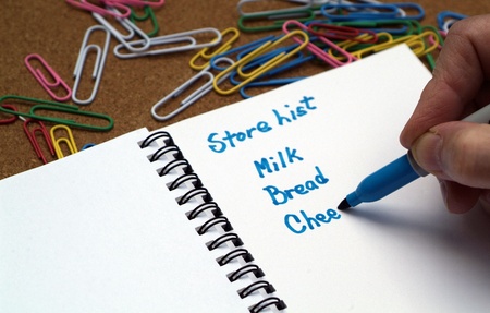 person writing a grocery store list with milk, bread and cheese.の写真素材