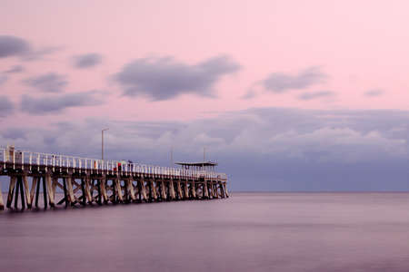 Largs Bay Jetty with pink dawn sky and smooth ocean just before sunrise.の写真素材
