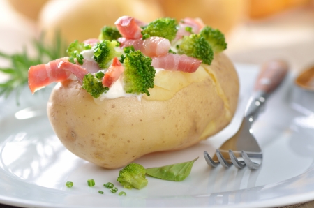 Baked potato stuffed with fried bacon strips, broccoli, chives and creme fraicheの写真素材