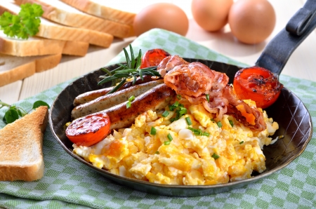 Scrambled eggs with fried bacon and sausagesの写真素材
