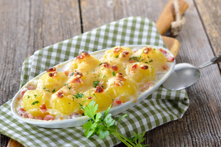 Hearty potato dumplings baked with cheese and bacon, freshly served from the ovenの写真素材