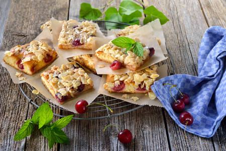 Fresh Austrian yeast cake with cherries and crunchy almond caramel served on a shabby cooling rackの写真素材