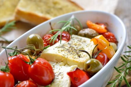 Warm Greek appetizer: Baked feta cheese with green olives, cherry tomatoes, peppers, onions and...