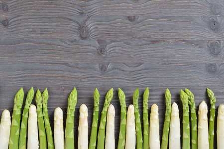Fresh Bavarian white and green asparagus from Schrobenhausen in a row on dark wood with copy spaceの写真素材
