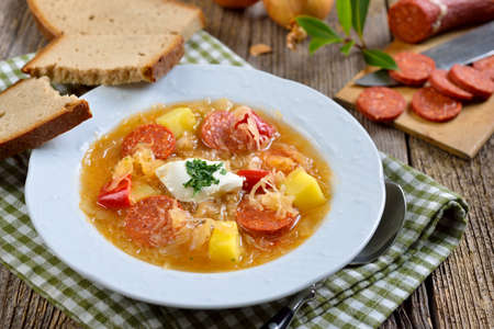 Delicious German sauerkraut soup with slices of spicy paprika sausage, served with farmers breadの写真素材