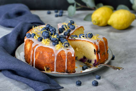 Lemon blueberry cake covered with sweet sugar icing, berries and lemon zestの写真素材