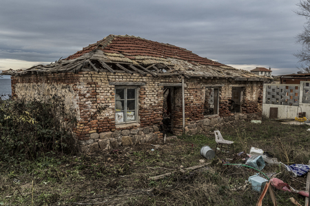 an old house destroyed in time, was once a home. a house on the sea shore not windy, damp and poor weather. abandoned and unsupported house turned into ruinsの写真素材