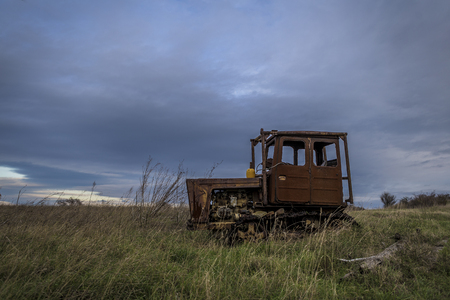 rusty and forgotten tractors stranded and left in the levels ruined by time. an old machine abandoned in the field of a dramatic blue sky background.の写真素材