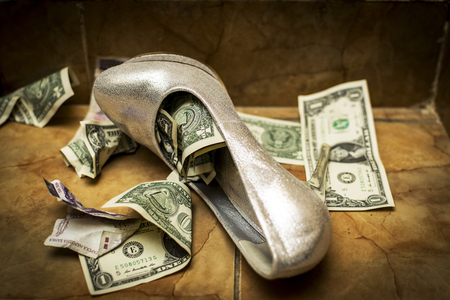 a white white wedding shoe full of dollars and currency. ritual at some weddings-the shoe is filled with money then the bride is given to the groom.の写真素材