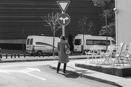 woman standing in front of a road sign and wondering where to go. choosing where to go. dilemma which way to catch.の写真素材