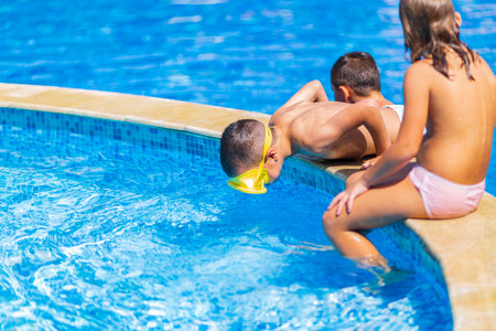 children jump, swim and play in the pool on a beautiful sunny summer day.  fun for kids on sunny summer days.の写真素材
