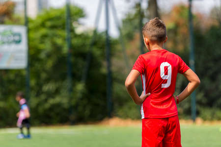 children play football on a green field. motion effect. children in a red team play against children...