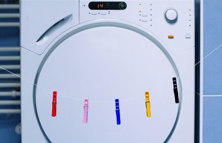 Running tumble drying versus traditional way of drying laundry. Dried clothes in closed tumble dryer and clothesline with clothespins.の写真素材