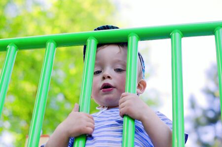 Little sad boy behind a fence. Child concept.の写真素材