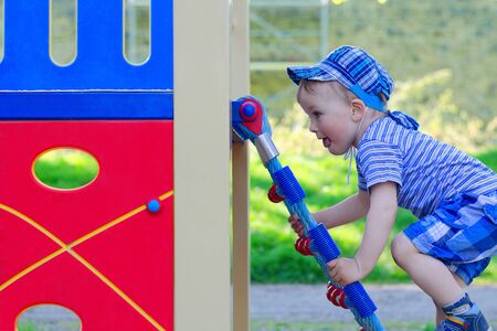 Cute Toddler climbs enthusiastically on the ladder in the playground.の写真素材