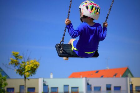 Boy swinging over roofs of houses. He wears helmet because of safety.の写真素材